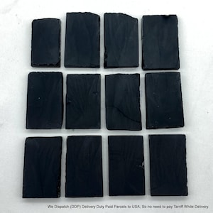 May include: Twelve rectangular black slate tiles arranged in a grid of three rows and four columns. Each tile features a dark, matte finish with natural, slightly uneven edges and subtle surface textures, presenting a uniform appearance.