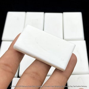 May include: A rectangular, smooth, white stone tile with a matte finish. The tile has a clean, solid white surface with subtle, faint grey marbling patterns visible across its flat, uniform face. It is presented as a single, solid piece.