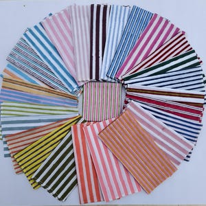 May include: A collection of rectangular fabric napkins arranged in a circular fan pattern. Each napkin features a distinct colour combination of vertical stripes, including shades of pink, blue, green, yellow, orange, red, and brown on white.
