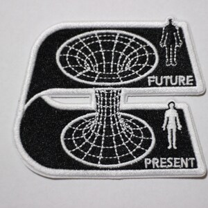 May include: Black and white embroidered patch depicting a person standing in front of a black hole, with the words "FUTURE" and "PRESENT" below.