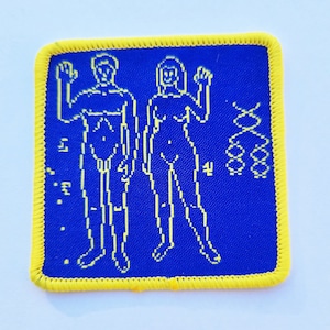 May include: A blue fabric patch with a yellow border. The patch features a pixelated image of two figures, a male and a female, standing side-by-side. The figures are outlined in yellow and have a pixelated design. To the right of the figures is a pixelated image of a double helix, also outlined in yellow.