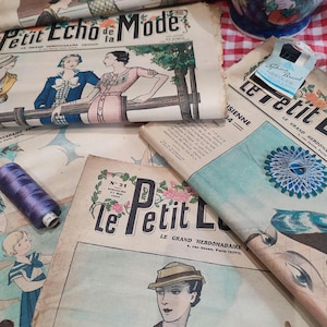 Könnte beinhalten: Eine Sammlung von Vintage-Modezeitschriften aus Frankreich mit Illustrationen stilvoller Figuren in historischer Kleidung. Die Zeitschriften sind gealtert und weisen sichtbare Gebrauchsspuren auf und enthalten den Text "Petit Echo de la Mode" und "Le Petit L". Eine Spule lila Fadens und eine blau-weiß blumige Vase sind ebenfalls zu sehen.