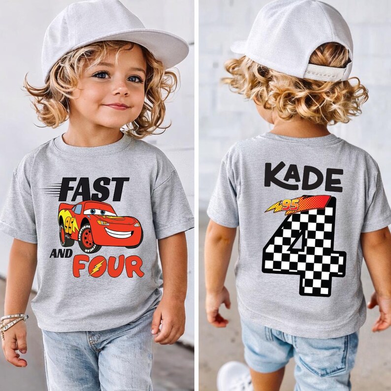 Pu&ograve; includere: Una t-shirt grigio melange con la grafica di un'auto da corsa rossa e la scritta FAST AND FOUR sul davanti, e il nome KADE sopra un grande numero 4 a scacchi con un fulmine sul retro, abbinata a un cappellino da baseball bianco.