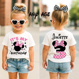 May include: A young child wearing a white t-shirt with a Minnie Mouse design and the text "IT'S MY BIRTHDAY". The back of the shirt has the name "Juliette" and the number "3". The child is also wearing denim shorts and heart-shaped sunglasses.