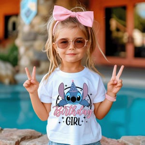 May include: A young girl wearing a white t-shirt with a Stitch graphic and the words "Birthday Girl". She is also wearing a pink bow, sunglasses, and a pink bracelet. The girl is smiling and giving a peace sign.