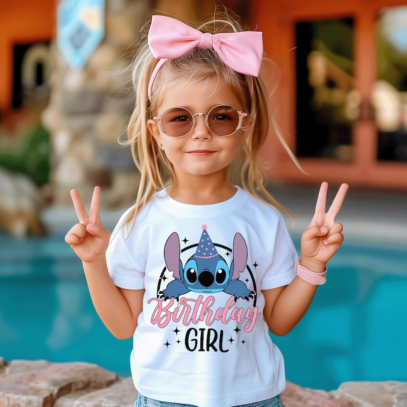 May include: A young girl wearing a white t-shirt with a Stitch graphic and the words "Birthday Girl". She is also wearing a pink bow, sunglasses, and a pink bracelet. The girl is smiling and giving a peace sign.