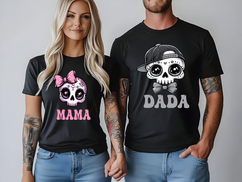May include: Two black t-shirts featuring graphic skull illustrations. The left shirt displays a skull with a pink polka-dot bow and the text MAMA in pink. The right shirt features a skull wearing a black baseball cap and bow tie with the text DADA.