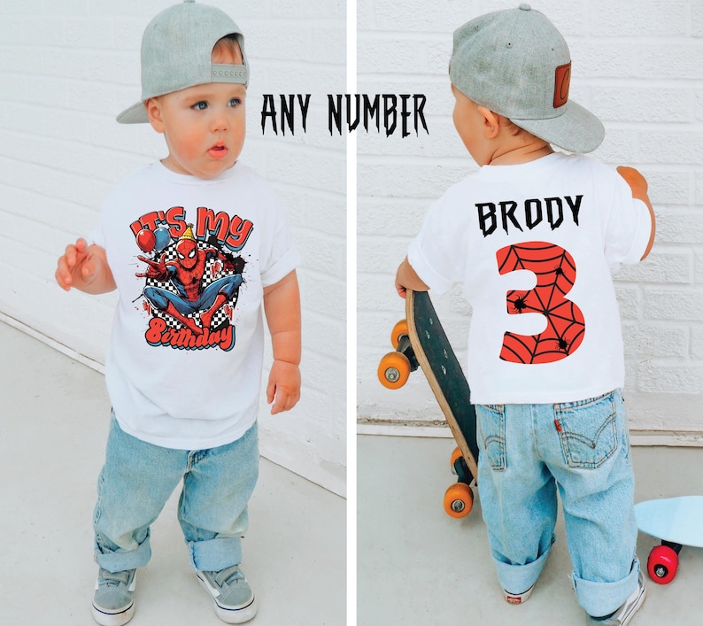 May include: A child in a white t-shirt featuring a Spider-Man design and the words "It's My Birthday". The child is also wearing blue jeans and a grey baseball cap. The back of the shirt has the name "Broddy" and the number "3".