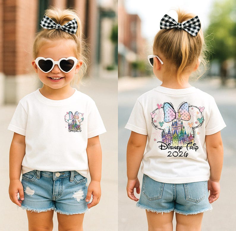 Pu&ograve; includere: Una bambina indossa una maglietta bianca e pantaloncini di jeans. La maglietta presenta una grafica colorata di un castello e un fiocco, con la scritta "Disney Trip 2020". La bambina indossa anche occhiali da sole a forma di cuore e un fiocco a scacchi bianco e nero.