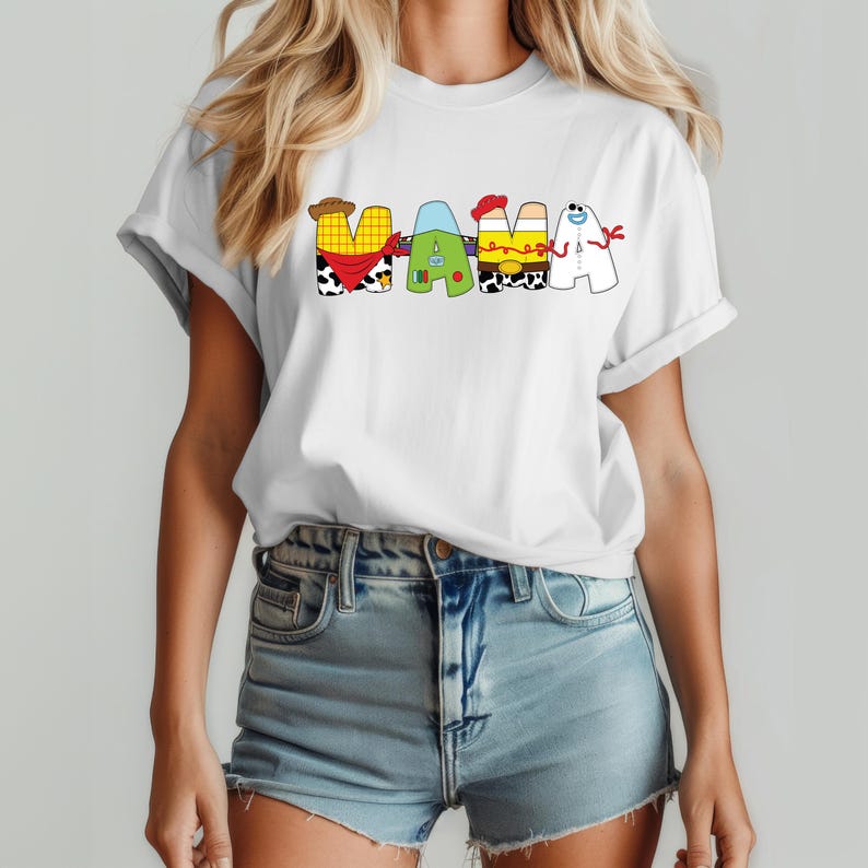 May include: White t-shirt with the word "MAMA" in colorful, cartoon-style letters. The letters are designed to resemble characters from a popular animated movie. The shirt is worn by a person in blue jean shorts.