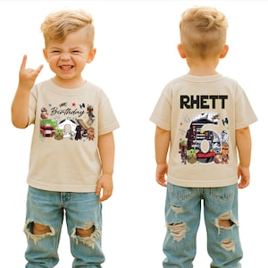 May include: Tan short-sleeved t-shirt with a Star Wars-themed birthday design. The front features the word "Birthday" and various characters. The back of the shirt displays the name "Rhett" above a large number "6" with more characters.