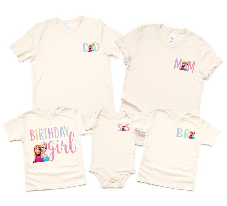 K&ouml;nnte beinhalten: Eine Sammlung cremefarbener T-Shirts und ein Body. Die Shirts haben kurze &Auml;rmel und zeigen die W&ouml;rter "DAD", "MOM", "BR" und "BIRTHDAY girl" in Pastellfarben, zusammen mit Bildern von Zeichentrickfiguren. Der Body hat die Buchstaben "S S".
