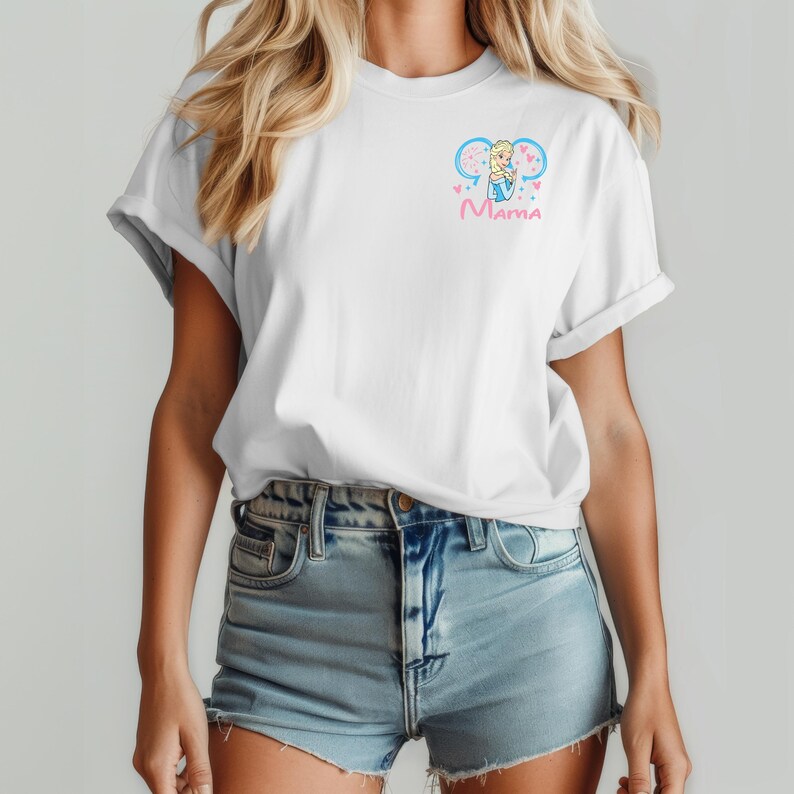 May include: A white short-sleeve t-shirt featuring a small graphic on the left chest. The design includes a cartoon character with blonde hair in a blue dress, framed by light blue mouse ears and pink hearts, with the word Mama written below.