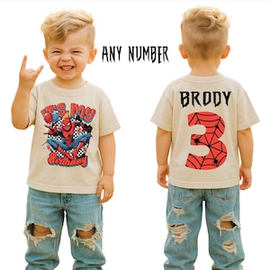 May include: A beige t-shirt featuring a Spider-Man graphic and the text "It's My Birthday" on the front. The back of the shirt displays the name "Brody" and the number "3" with a spiderweb design. The shirt is worn by a child.