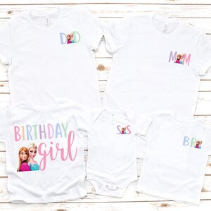 K&ouml;nnte beinhalten: Wei&szlig;e T-Shirts mit bunten Grafiken und Text. Ein Shirt sagt "DAD" und ein anderes sagt "MOM", beide mit einem Cartoon-Bild. Ein Shirt sagt "BIRTHDAY girl" mit einem Cartoon-Bild. Andere Shirts sagen "SIS" und "BRO".