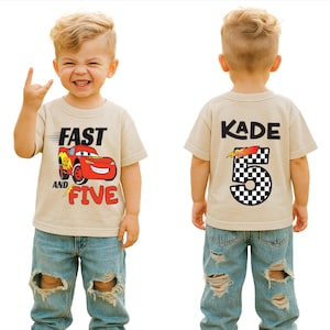 K&ouml;nnte beinhalten: Ein beiges T-Shirt mit einer roten Rennwagen-Grafik und dem Text FAST AND FIVE auf der Vorderseite sowie dem Namen KADE &uuml;ber einer gro&szlig;en karierten Zahl 5 auf der R&uuml;ckseite. Das Design enth&auml;lt ein Blitzsymbol und Bewegungslinien in Schwarz und Rot.