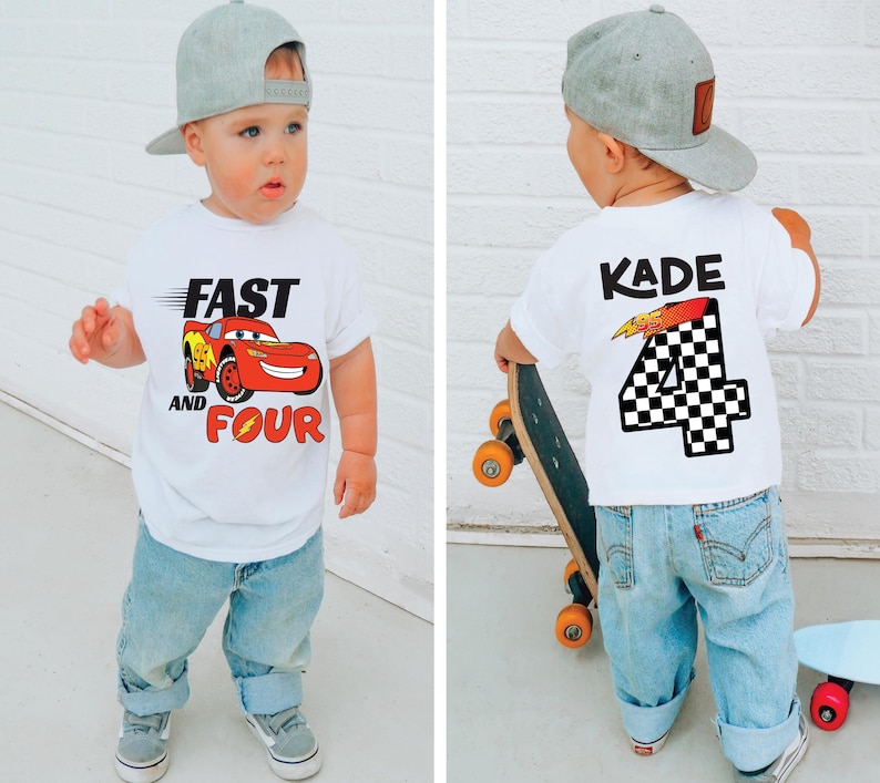 Pu&ograve; includere: Una t-shirt bianca a maniche corte con la grafica di un'auto da corsa rossa e la scritta FAST AND FOUR sul davanti, e il nome KADE sopra un grande numero 4 a scacchi sul retro, abbinata a un berretto da baseball grigio e jeans azzurri.