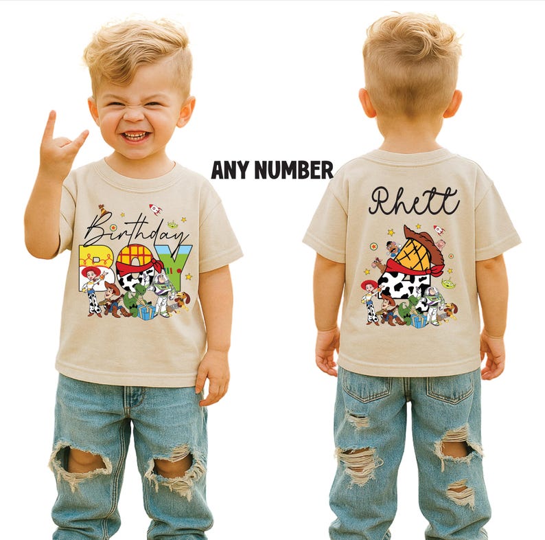 May include: A tan short-sleeved t-shirt with a colorful graphic featuring characters and the text "Birthday Boy." The back of the shirt has the name "Rhett" and a similar graphic. The shirt is worn by a child.