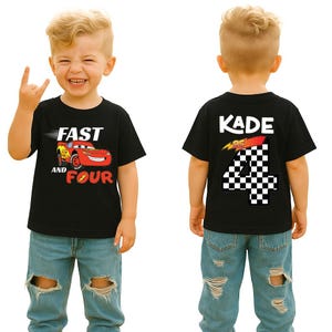 Pu&ograve; includere: Una t-shirt nera a maniche corte con una grafica di un'auto da corsa rossa sul davanti con il testo FAST AND FOUR. Il retro della maglietta mostra il nome KADE sopra un grande numero 4 con motivo a scacchi e una grafica a fulmine.