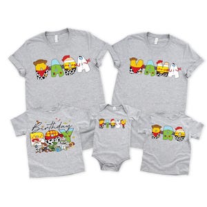 May include: A collection of gray t-shirts and a onesie featuring colorful cartoon character designs. The shirts spell out "MAMA", "DADA", and "BRO", with a "Birthday" design. The onesie and shirts are short-sleeved.