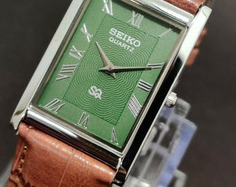 Relógio masculino Seiko Slim vintage restaurado, com mostrador verde e pulseira marrom, 26 mm, quartzo, retangular.