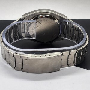 May include: A stainless steel Seiko watch with a silver metal band. The watch face is black with silver text and hands. The back of the watch has the text "Water Resistant Stainless Steel" and the model number 2N639F.