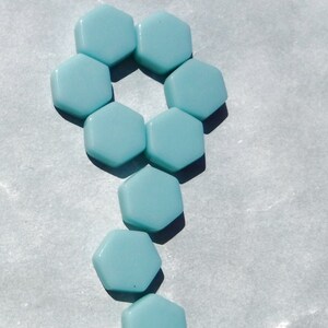 May include: Two arrangements of light blue hexagonal tiles. One arrangement is a vertical line of tiles, the other is a circle of tiles with a tail of tiles.