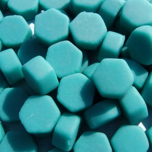 May include: A close-up of a pile of teal blue hexagonal shaped beads.