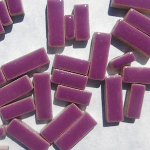 May include: A collection of purple ceramic tiles in various sizes and shapes. The tiles are smooth and glossy, with a slight sheen.