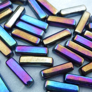 Puede incluir: Un conjunto de cuentas rectangulares iridiscentes. Las cuentas tienen un brillo metálico con colores que cambian del azul al púrpura y al dorado. Los bordes redondeados de las cuentas capturan la luz, creando un efecto brillante. Estas cuentas son adecuadas para la fabricación de joyas y manualidades.