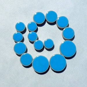 May include: Three arrangements of blue and white ceramic circles. One is a square, another a spiral, and the last is a vertical line. The circles have a bright blue center and a white border, set against a light gray background.