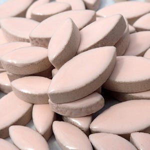 Pode incluir: Um monte de doces de cor rosa p&aacute;lido, de forma oval, dispostos em um padr&atilde;o aleat&oacute;rio. Os doces s&atilde;o lisos e brilhantes.