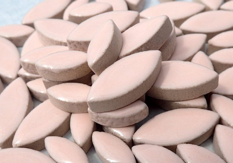 Pode incluir: Um monte de doces de cor rosa p&aacute;lido, de forma oval, dispostos em um padr&atilde;o aleat&oacute;rio. Os doces s&atilde;o lisos e brilhantes.