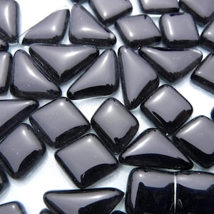 May include: A collection of glossy, black glass mosaic tiles in various shapes, including squares, triangles, and rectangles. The tiles have rounded edges and reflect light, creating a shiny appearance. These tiles are suitable for craft projects.