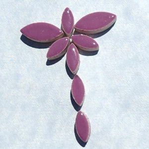 Pode incluir: Um desenho de mosaico de azulejos em forma de flor roxa, feito de pequenos azulejos ovais. Os azulejos est&atilde;o dispostos em forma de flor com um caule.