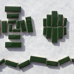 May include: A top-down view shows dark green rectangular tiles arranged in different formations. Some tiles are grouped to create a cross-like shape, while others form a circular pattern. A few tiles are scattered in a curved line.