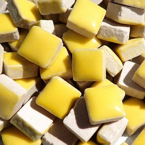 May include: A pile of small, square ceramic tiles with a yellow glaze. The tiles are arranged in a random pattern, with some tiles overlapping others.