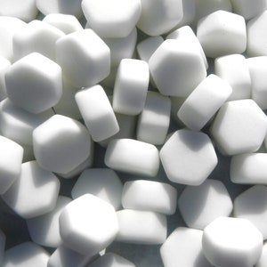May include: A collection of white hexagonal glass tiles. The tiles are smooth and have a matte finish.