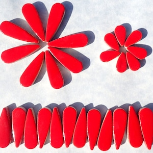 May include: A set of red ceramic tiles in the shape of teardrops. The tiles are arranged in two flower shapes and a row.