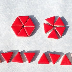 May include: A collection of red triangular ceramic tiles. The tiles are arranged in three different patterns: a hexagon, a circle, and a row.
