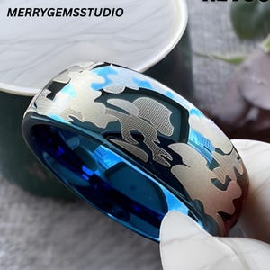 May include: A blue and silver ring with a unique pattern. The ring has a shiny blue interior and a silver design on the exterior. The ring is a piece of jewelry.