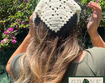 May include: A cream-colored triangular crochet headscarf featuring an intricate openwork pattern with a scalloped edge. The accessory is worn over long hair and includes a rectangular logo patch that reads GROVE HAND MADE with a leaf icon.