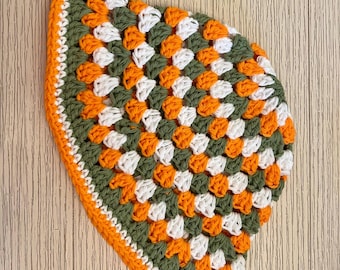May include: Handmade crochet hat in a granny square pattern. The hat features a color scheme of olive green, white, and orange, with an orange border. The text "GROVE HAND MADE" is displayed on a rectangular label.