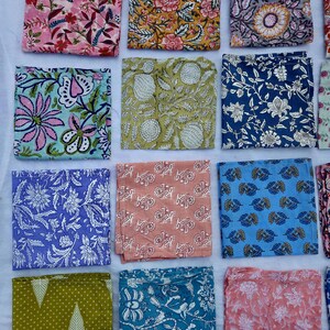 Könnte beinhalten: Eine Sammlung farbenfroher, quadratischer Stoffservietten mit verschiedenen floralen und botanischen Mustern. Die Servietten weisen eine Reihe von Farben auf, darunter Rosa, Gelb, Blau, Grün und Pfirsich. Jede Serviette hat ein einzigartiges Design mit detaillierten Drucken.