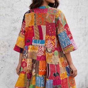 May include: A colorful patchwork jacket with a variety of patterns and colors, including red, orange, yellow, and blue. The jacket has a loose fit with three-quarter sleeves and a ruffled hem. The garment is made of multiple fabric pieces sewn together.