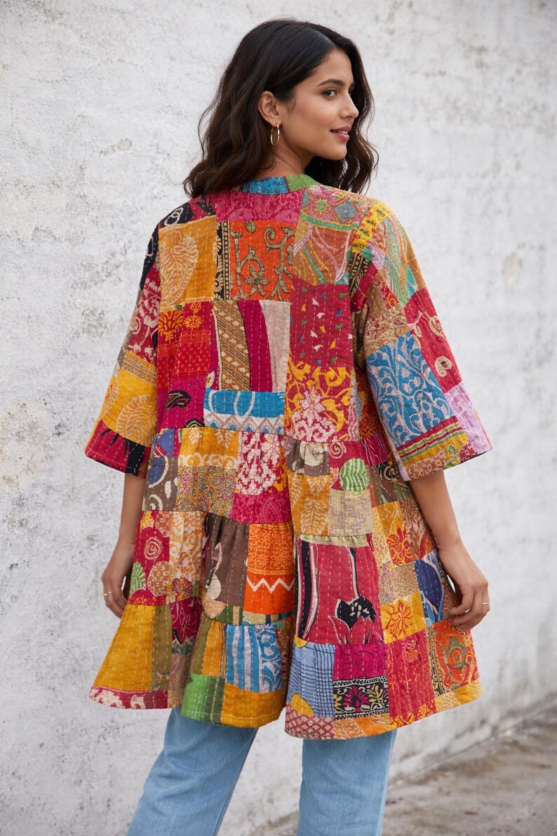 May include: A colorful patchwork jacket with a variety of patterns and colors, including red, orange, yellow, and blue. The jacket has a loose fit with three-quarter sleeves and a ruffled hem. The garment is made of multiple fabric pieces sewn together.