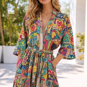 Könnte beinhalten: Bunter Patchwork-Bademantel mit Bindegürtel und Taschen. Der Bademantel zeigt eine lebendige Mischung aus Mustern, darunter Herzen, Blumen und geometrische Formen in Blau-, Gelb-, Rot- und Grüntönen. Die Ärmel sind dreiviertellang.