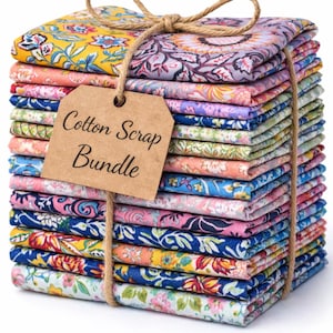 May include: A stack of colorful cotton fabric scraps tied with twine. The bundle includes various floral and patterned designs in shades of yellow, blue, pink, and purple. A brown tag reads "Cotton Scrap Bundle."