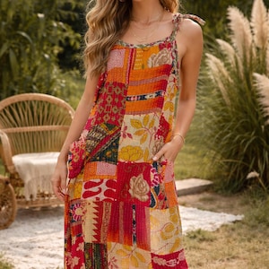 Könnte beinhalten: Ein Patchwork-Midikleid in Rot-, Orange- und Gelbtönen. Das Kleid hat einen quadratischen Ausschnitt, Bindeträger und eine lockere Passform. Der Stoff ist eine Mischung aus floralen und geometrischen Mustern, mit zwei Taschen.