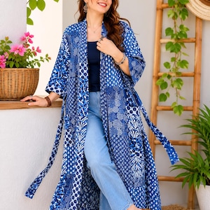 May include: A long, open-front kimono-style robe featuring a patchwork design of various blue and white geometric and floral patterns. The garment has three-quarter length sleeves, a tie waist, and a straight hemline that falls below the knees.